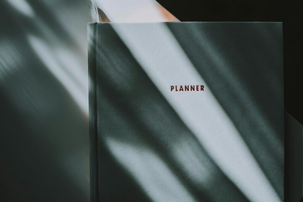 Close-up of a planner with shadows on the cover, creating a moody indoor atmosphere.